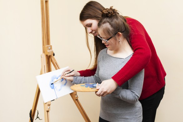 side-view-of-woman-helping-girl-with-down-syndrome-paint